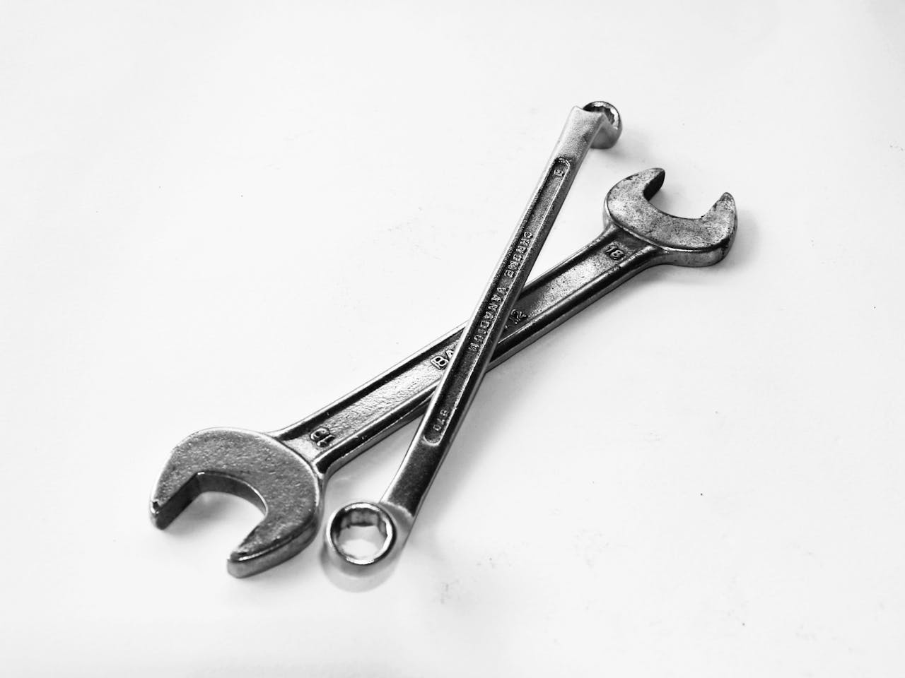 services-img-01 A pair of crossed metal wrenches on a clean white surface.